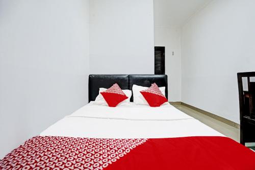 a bed with red and white pillows on it at Hotel O Kambang Iwak Area Near Kambang Iwak Park Formerly Kerangga in Palembang