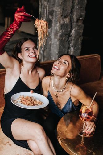 two women sitting on a couch with a plate of food at La Folie Douce Hotels Chamonix in Chamonix-Mont-Blanc