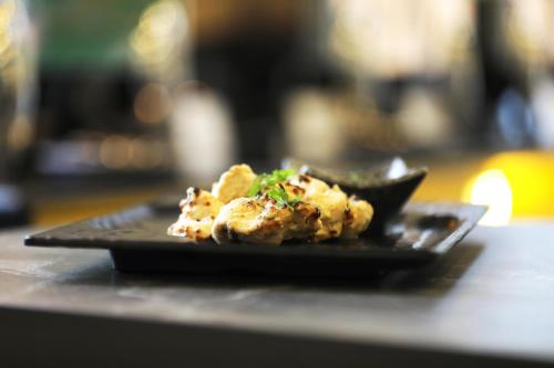 a black plate with food on a table at HUE GUH The Porto Candolim in Calangute