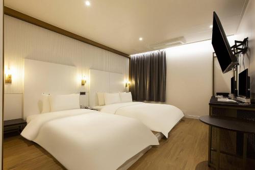 a hotel room with two beds and a flat screen tv at Grazie Hotel Tanhyeon in Goyang