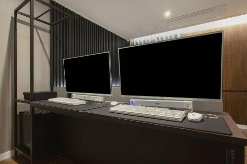 a desk with two computer monitors and a keyboard and mouse at Grazie Hotel Tanhyeon in Goyang