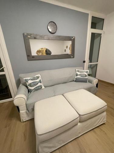 a living room with a couch and a clock on the wall at Acquadolce Apartment in Baveno