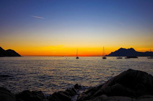 a sunset over the ocean with boats in the water at Hôtel & Résidence Le Subrini in Porto Ota