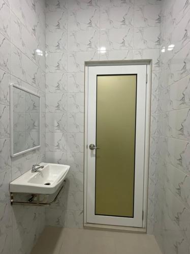 a white bathroom with a sink and a mirror at Timeless Cottage KB in Kota Bharu