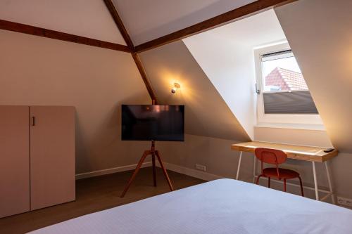 a bedroom with a bed and a desk and a television at The Swiete Den Haag - 2 Stylish boutique apartments - Between city center and the beach in The Hague