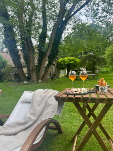 a picnic table with two glasses of wine on it at Le Clos des Songes in Blaru