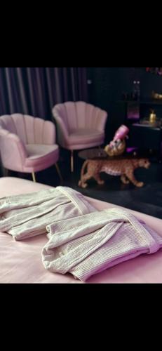 a bed with pink chairs and towels on it at Love Room Secret-private jacuzzi spa & cinéma Bucuresti in Voluntari
