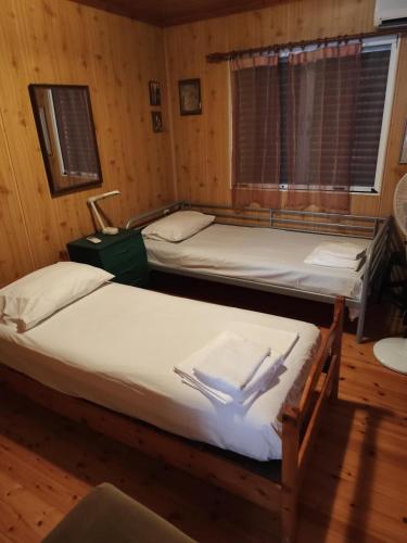two beds in a room with wooden walls at σπίτι - αγρόκτημα - Δ Γεωργά Χατζηράση οδός Χατζηράση in Porto Heli