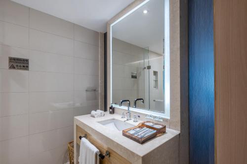 a bathroom with a sink and a mirror at Pearl River International Hotel - Canmetro line 11 YiJing Lu station in Guangzhou