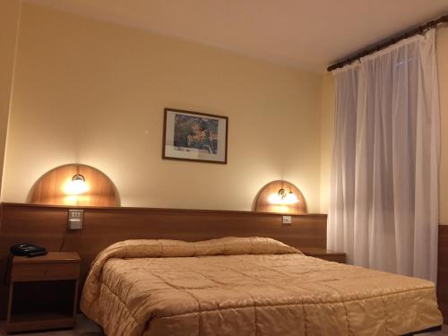 a bedroom with a bed and two lights on the wall at Hotel Rocco in Carugate