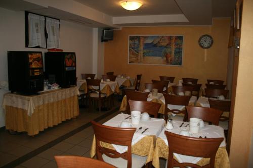 a dining room with tables and chairs and a clock at Hotel Rocco in Carugate