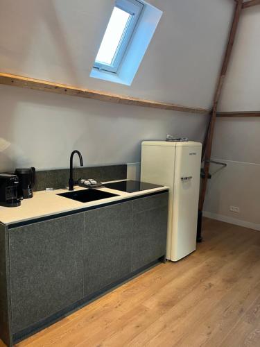 a kitchen with a sink and a refrigerator at Planq Suites in Gorinchem