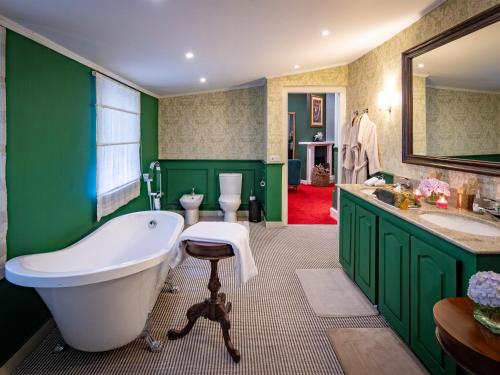 Un baño con paredes verdes, bañera y lavabo. en Hill Rise Luxury Villa & Stables by Edwards Collection, en Nuwara Eliya
