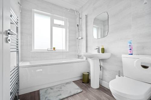 a white bathroom with a tub sink and a toilet at The Rock, Elegant 4 Bedroom House, Solihull, close to NEC, sleeps 8 in Birmingham