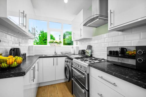 a kitchen with white cabinets and a stove top oven at The Rock, Elegant 4 Bedroom House, Solihull, close to NEC, sleeps 8 in Birmingham