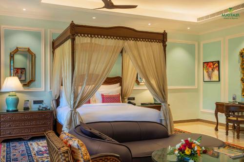 a bedroom with a canopy bed and a table at Mayfair Spring Valley Resort Guwahati in Guwahati