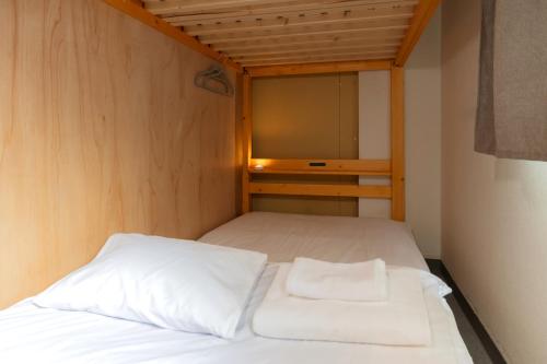 a bed with two white pillows in a small room at Dormitory Kinshu - ドミトリー錦繍 in Tokyo