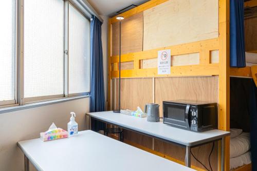 a small room with a microwave on a table at Dormitory Kinshu - ドミトリー錦繍 in Tokyo