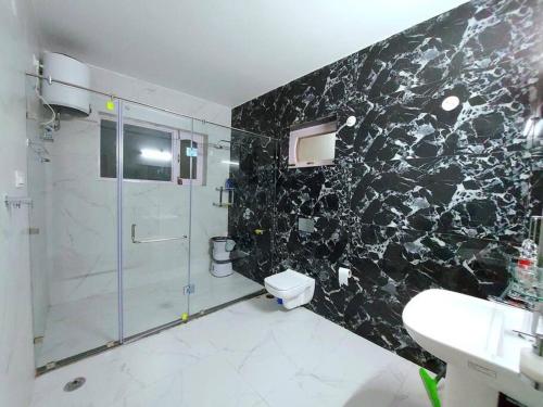 a bathroom with a shower and a toilet and a sink at BnBBuddy Himalayan 3BR Farmstay wid Lawn Near Manali in Manāli