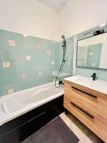une salle de bain avec une baignoire, un lavabo et un miroir dans l'établissement Le République 2, Gare, Centre-Ville, à Bourgoin-Jallieu