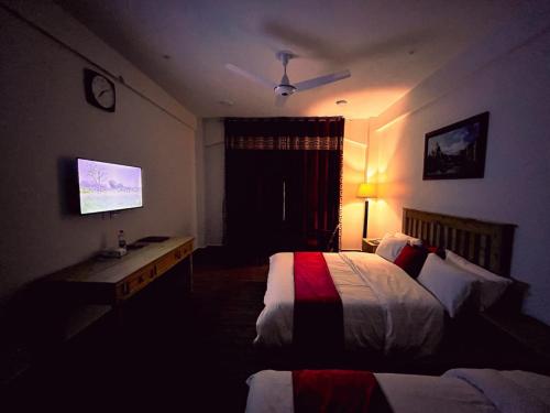 a hotel room with two beds and a television at Hispar Hotel Skardu in Skardu