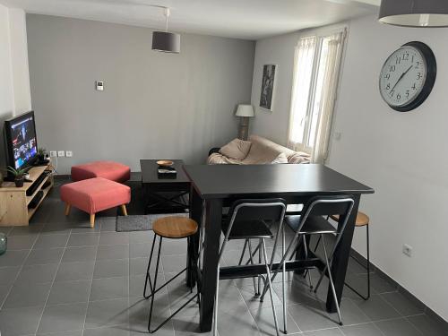 un soggiorno con tavolo, sedie e orologio di Proche Bordeaux centre : petite maison de ville +parking a Cenon
