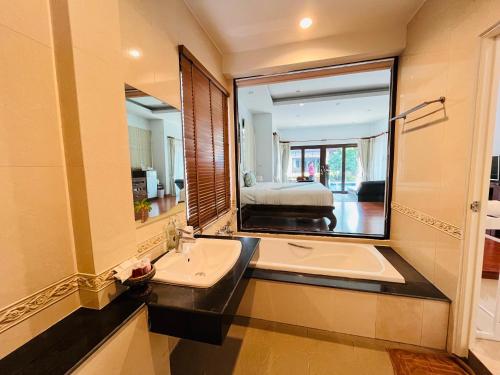a bathroom with a sink and a large mirror at Poolsawat Villa - SHA Plus in Lamai