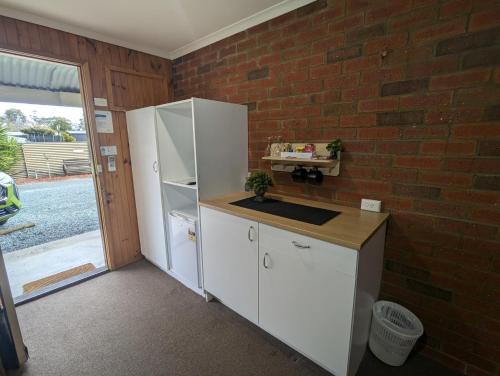 a kitchen with a white refrigerator and a brick wall at Kyabram Country Motel in Kyabram