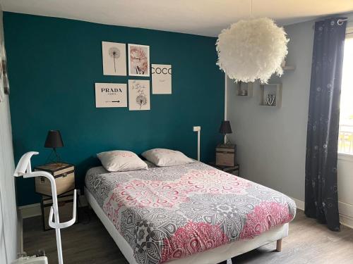 une chambre avec un lit et un mur bleu dans l'établissement Le cozy des tuilières, 2 ch, à Limoges