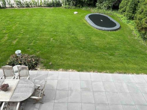 a patio with a table and a trampoline in the grass at Helt nyt hus i idyllisk landsby in Vallensbæk
