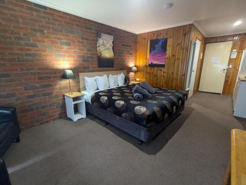 a bedroom with a bed with a brick wall at Kyabram Country Motel in Kyabram