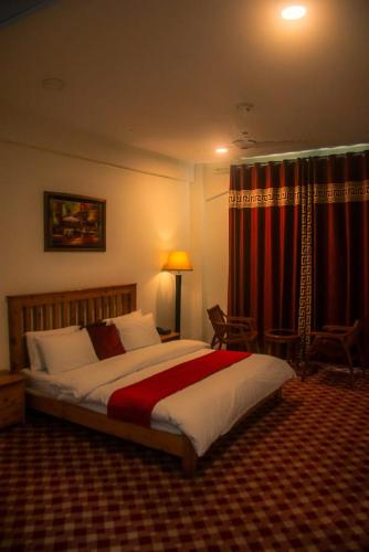 a bedroom with a large bed with red curtains at Hispar Hotel Skardu in Skardu
