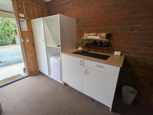 a kitchen with a white refrigerator and a brick wall at Kyabram Country Motel in Kyabram