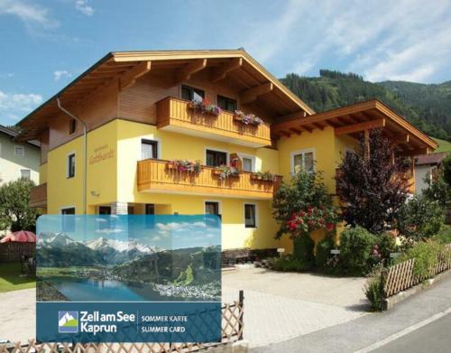 a yellow house with a balcony and a sign in front of it at Apartmenthaus Gotthardt in Kaprun