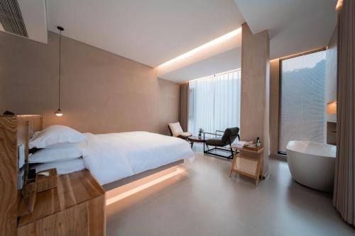 a bedroom with a bed and a bath tub and a sink at 云漫山居民宿 in Xinglong