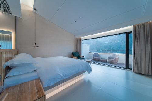 a bedroom with a bed and a large window at 云漫山居民宿 in Xinglong
