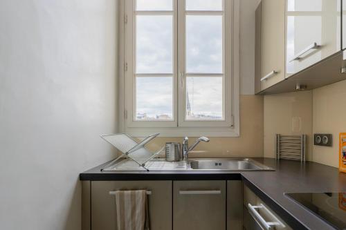 une cuisine avec un évier et une fenêtre dans l'établissement Luxury and Comfort in the Heart of Paris, à Paris