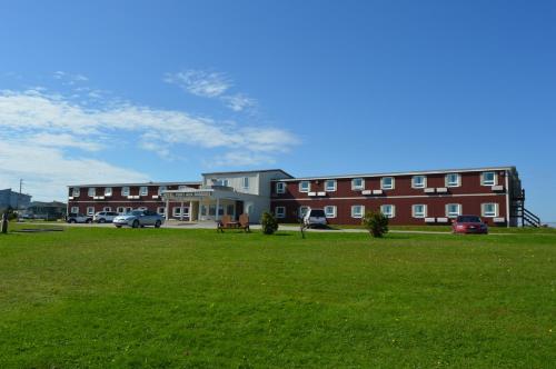 a large building with a grass field in front of it at Hotel Port Aux Basques in Channel-Port aux Basques