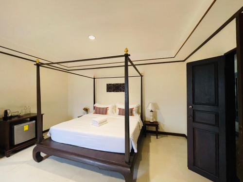 a bedroom with a canopy bed with white sheets at Na Thapae Chiangmai Hotel in Chiang Mai