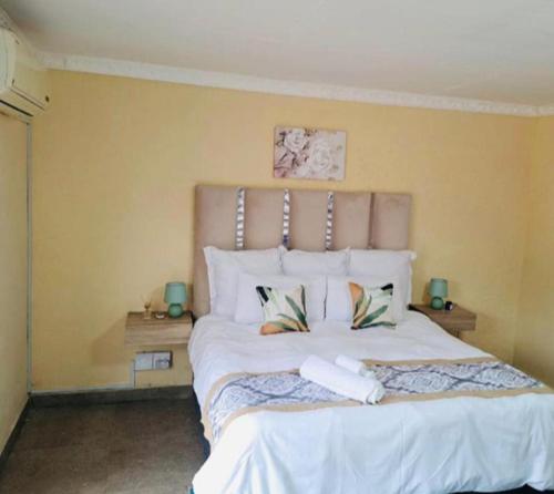a bedroom with a large white bed with two pillows at Glamour C-rane lodge in Phalaborwa
