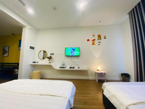 a room with two beds and a tv on the wall at Căn hộ IB1011 Tự Doanh toà 21 tầng Flamingo Hải Tiến in Thanh Hóa