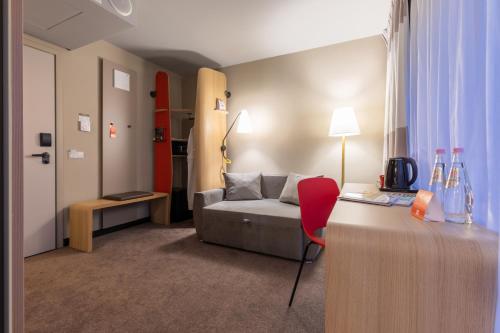 a room with a couch and a table with a red chair at ibis Tbilisi Stadium in Tbilisi City