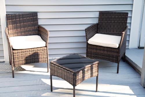 two wicker chairs and a stool on a porch at The Freedom HOME from HOME in New Bedford