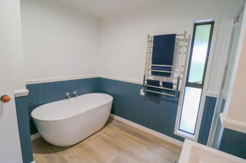 a white bath tub in a bathroom with blue walls at Moomaa Stay in Marton