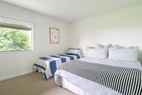 two beds in a white room with a window at Moomaa Stay in Marton