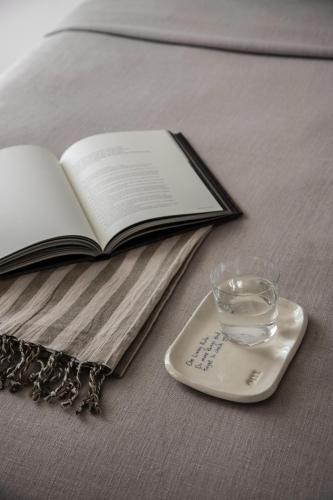 a book and a remote control on a table with a glass at Om Living Milos in Pollonia