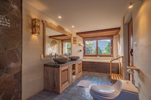 a bathroom with a toilet and a sink and a tub at Maha Hills Resort by Mahaprana Experience in Lovina