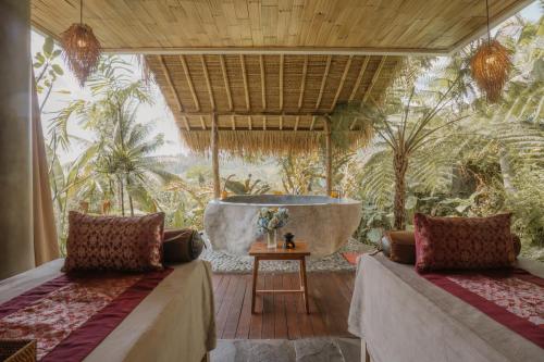 a room with two beds and a bath tub at Maha Hills Resort by Mahaprana Experience in Lovina