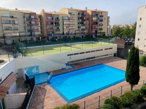 - une piscine avec un court de tennis dans un bâtiment dans l'établissement L'attrape rêves du Cap d agde, au Cap d'Agde