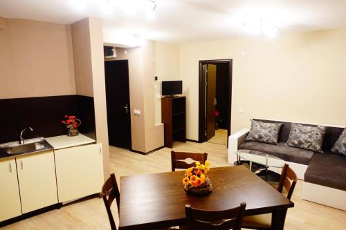 a kitchen and a living room with a table and a couch at ENIS Hotel с минерален басейн in Sapareva Banya